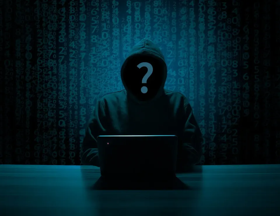 A hooded silhouette at a computer, the kind of attacker who targets unpatched phones
