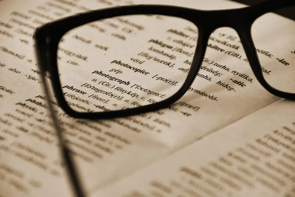 Language learning books and glasses on a table, linked to research on non-native English writers
