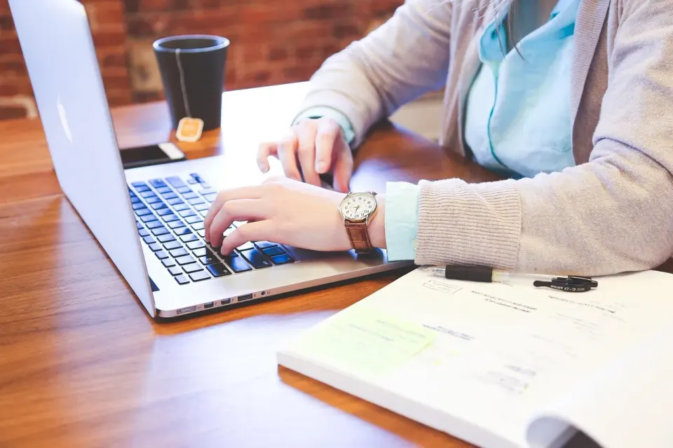 Hands typing on a laptop keyboard, the way most people put questions to a chatbot