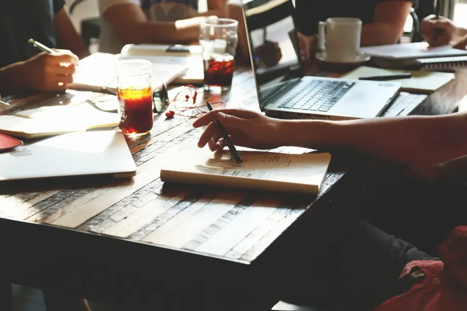 A laptop on a desk with a notebook, where long late-night chats often happen